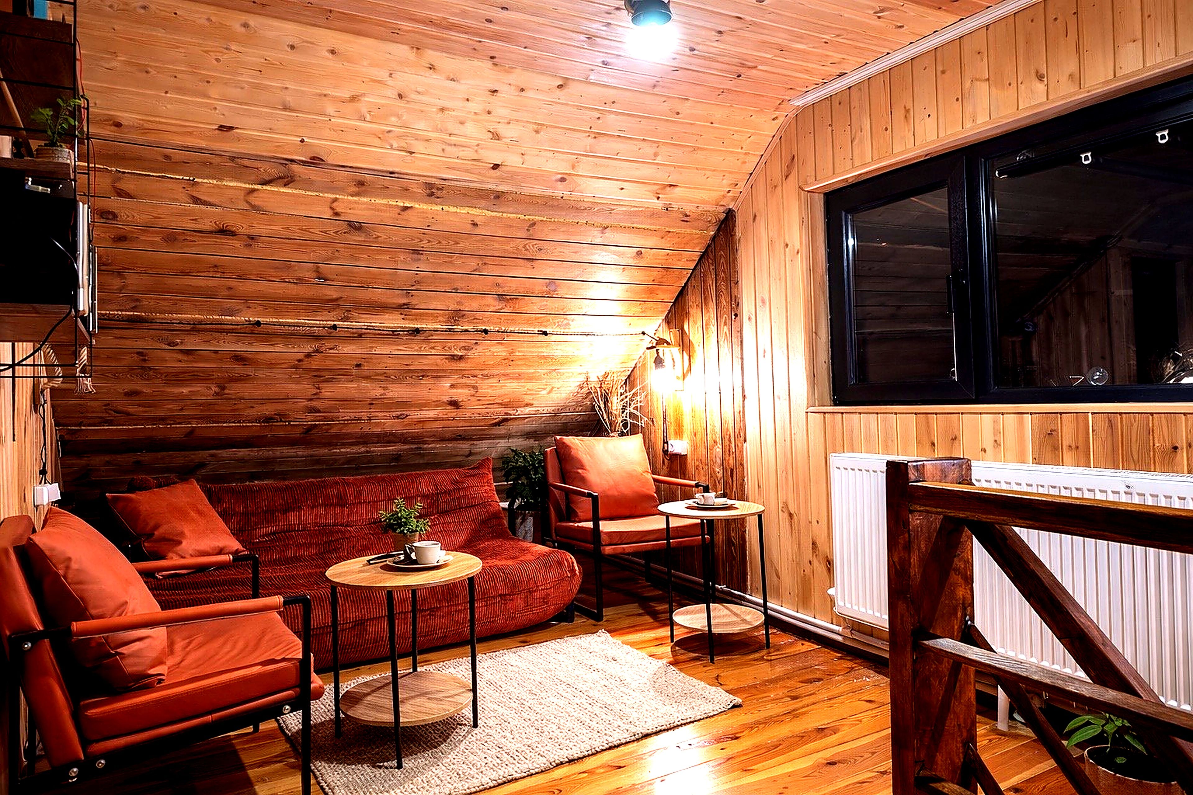 Une pièce chaleureuse avec des murs en bois, un canapé rouge, une petite table et une chaise.