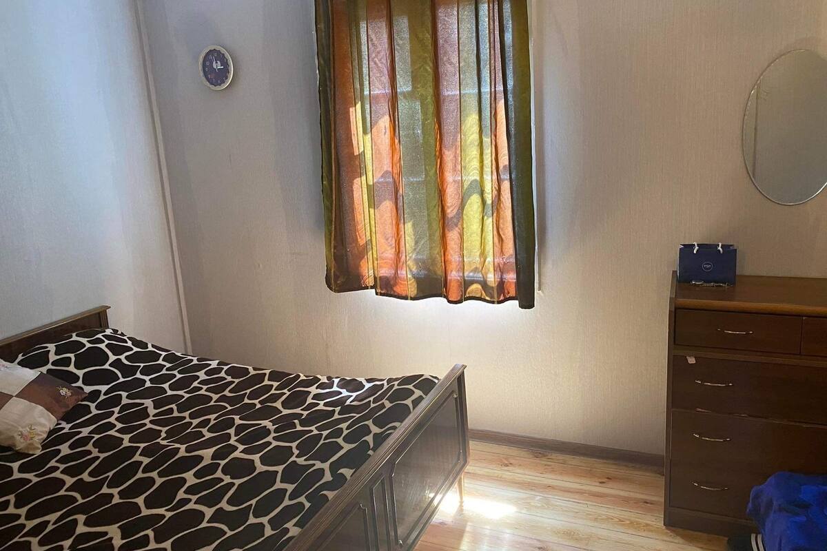 Ein Schlafzimmer mit Bett, Schminktisch, Spiegel und einem Fenster mit Vorhängen.