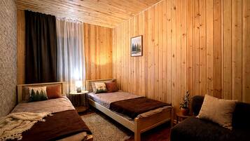 A wooden-paneled room with two beds, a nightstand, a lamp, and a framed picture on the wall.