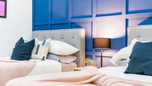 A hotel room with two beds, a blue accent wall, and a bedside lamp. - Beaux-Arts house in Condesa with rooftop (Ciudad de México)