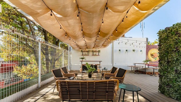 An outdoor patio with wicker furniture, a table, and chairs under a canopy. - Beaux-Arts house in Condesa with rooftop (Ciudad de México)