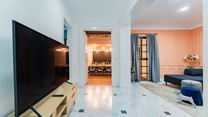 A modern living room with a flat-screen TV, a wooden entertainment unit, a dining area with a chandelier, and a cozy seating area with a sofa and ottoman. - Beaux-Arts house in Condesa with rooftop (Ciudad de México)