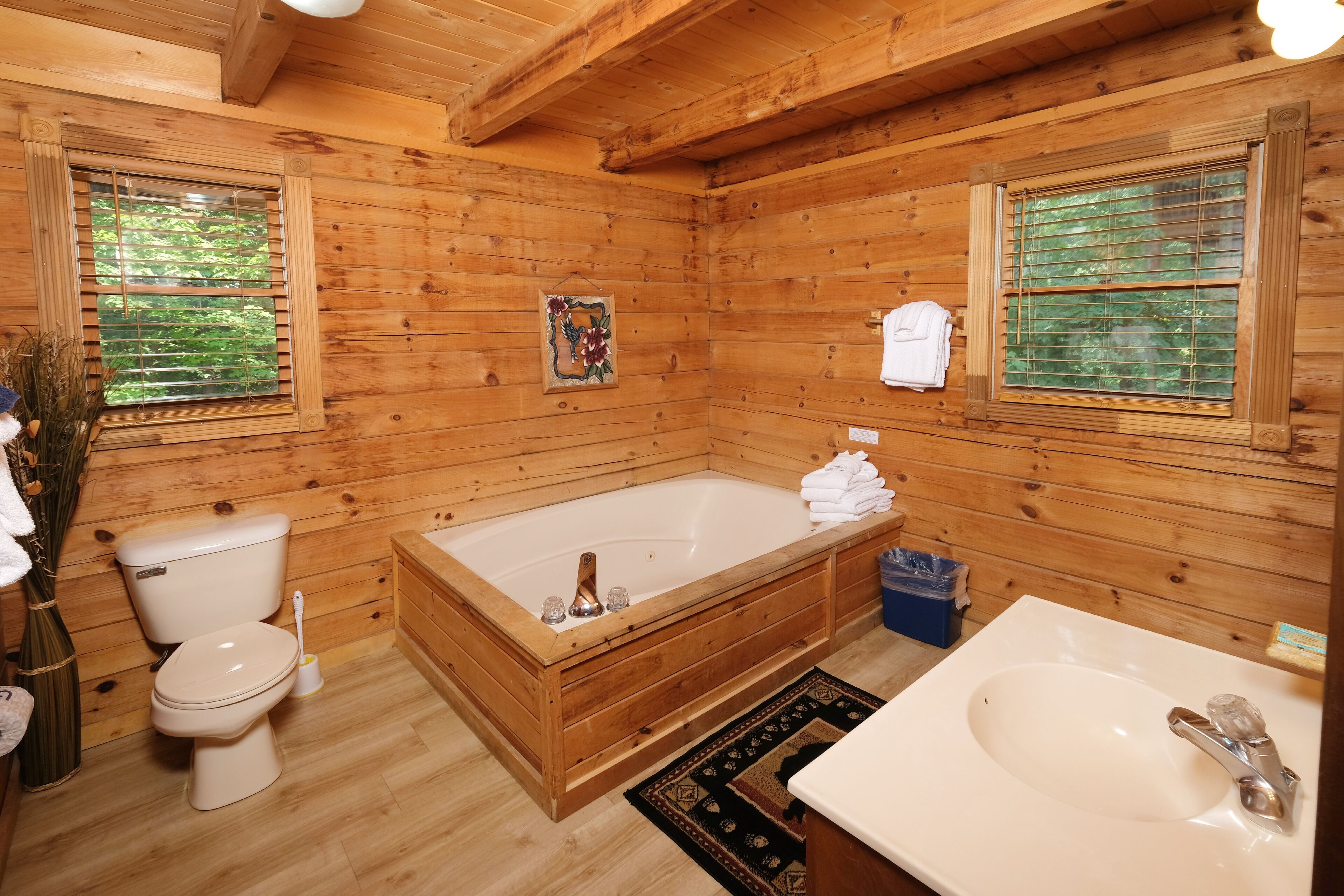Een houten badkamer in een vakantiehuisje, met een badkuip, toilet en wastafel.