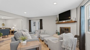 Un salon moderne avec des canapés gris, une table basse en bois et une cheminée.