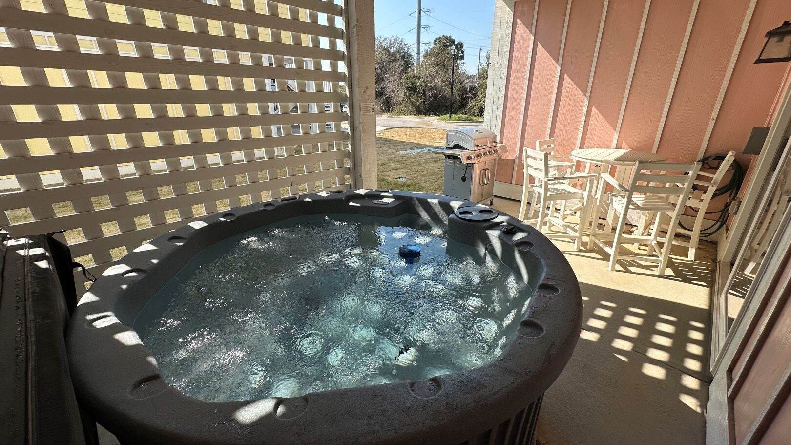 Un bain à remous doté d’une terrasse en bois et d’un espace patio avec des chaises.