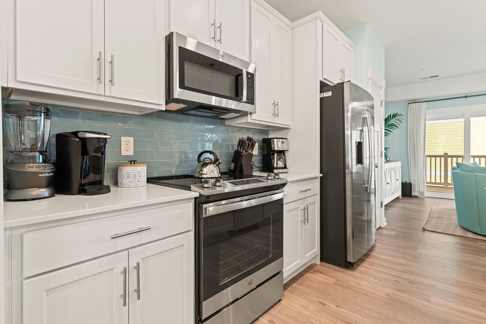 A modern kitchen with white cabinets, stainless steel appliances, and a coffee maker.