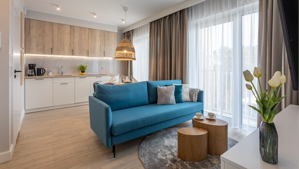 A modern living room with a blue sofa, a round coffee table, and a vase of tulips. - Vacation apartment by the sea, vacation on the island of Usedom, Apartment BALTYCKI A22 (Świnoujście)