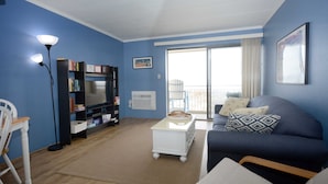 A living room with a blue wall, a sofa, a coffee table, a bookshelf, and a chair.