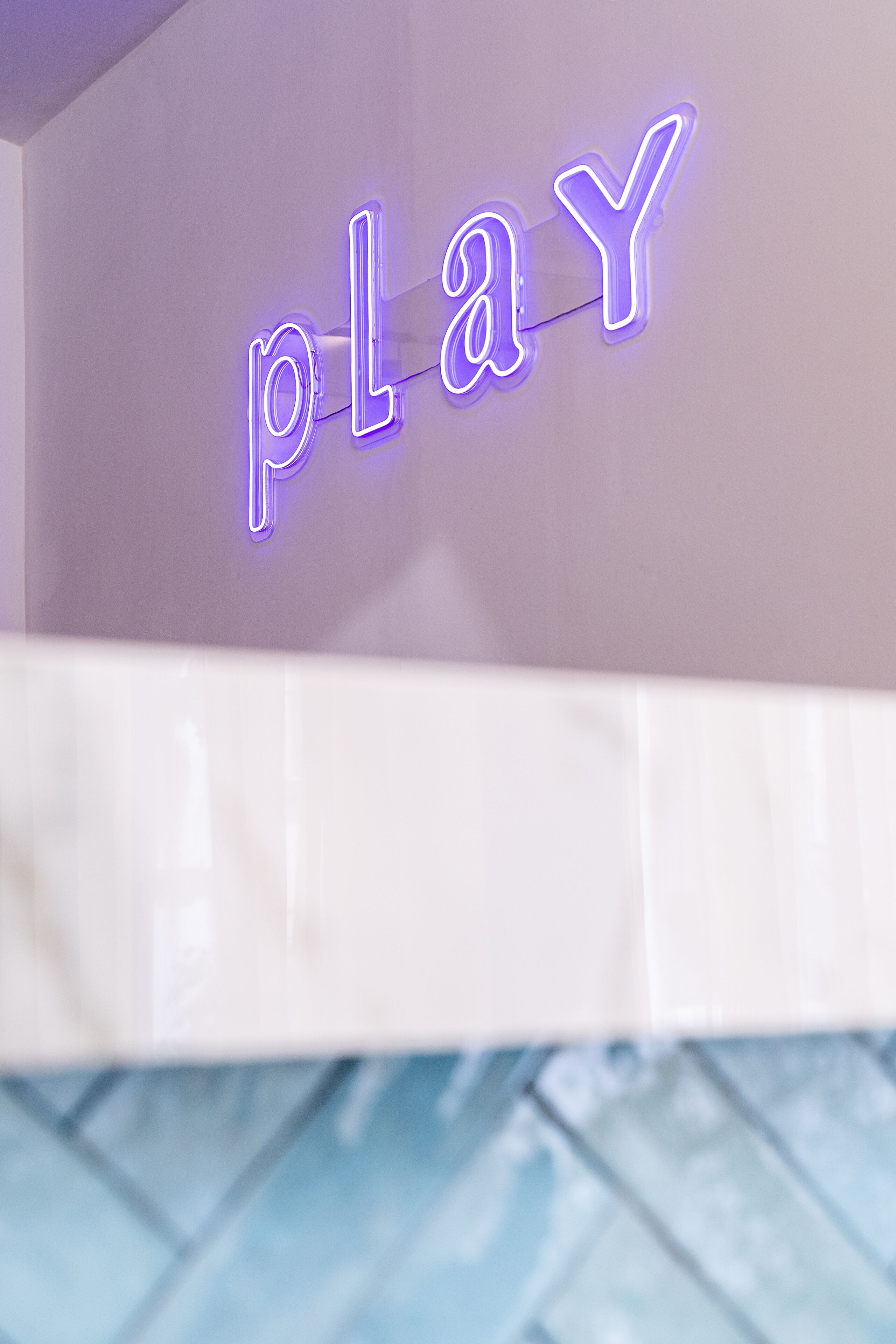 A neon sign spelling "PLAY" on a wall.