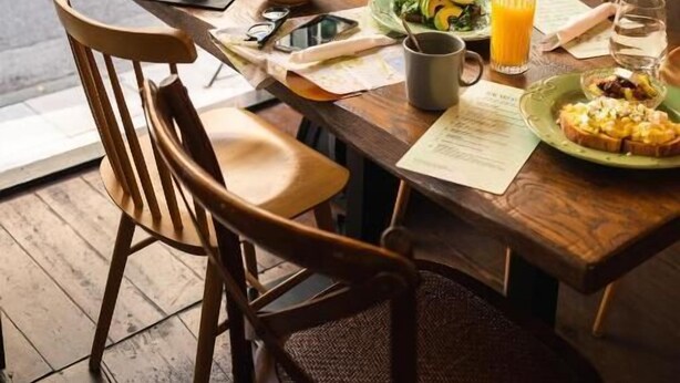 A dining table with chairs, a menu, and a glass of orange juice. - Play Psyri, a member of Brown Hotels (Athens)