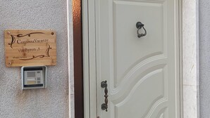A white door with a decorative handle and a small sign above it. - Vacation home byron (Contessa Entellina)