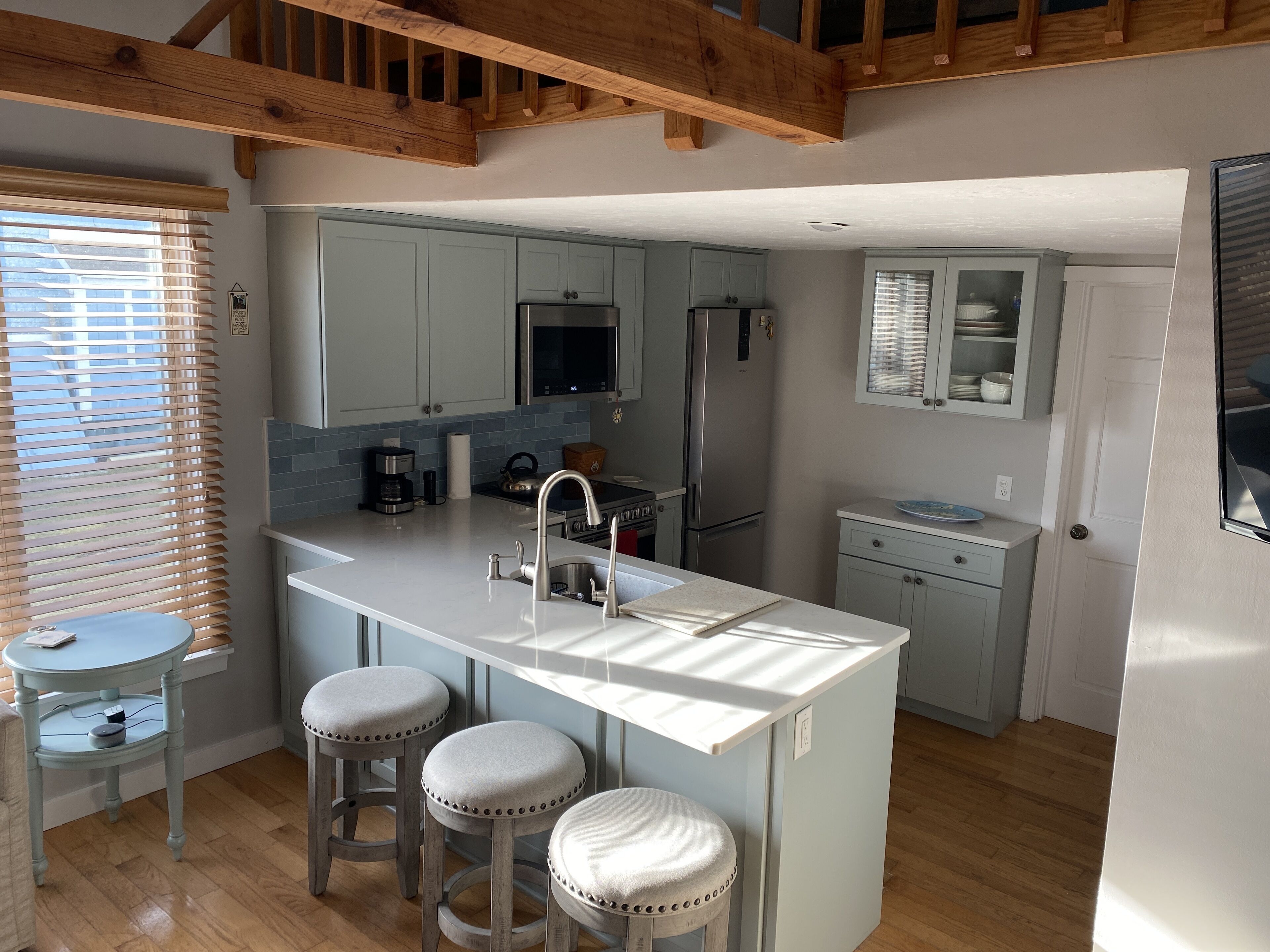A modern kitchen with a central island, bar stools, and built-in appliances.