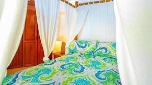 Una camera da letto con un letto a baldacchino, un'armadiatura in legno e una lampada da comodino.