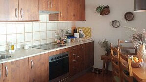 A kitchen with wooden cabinets, a dishwasher, and a dining area with a table and chairs.