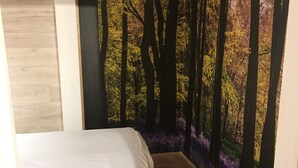 Un dormitorio con cama, suelo de madera y un mural temático de bosque.