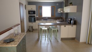 Cozinha moderna com ilha central, eletrodomésticos embutidos e uma janela.