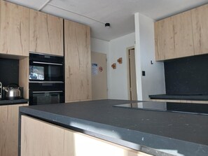 A kitchen with wooden cabinets, a black countertop, and stainless steel appliances.