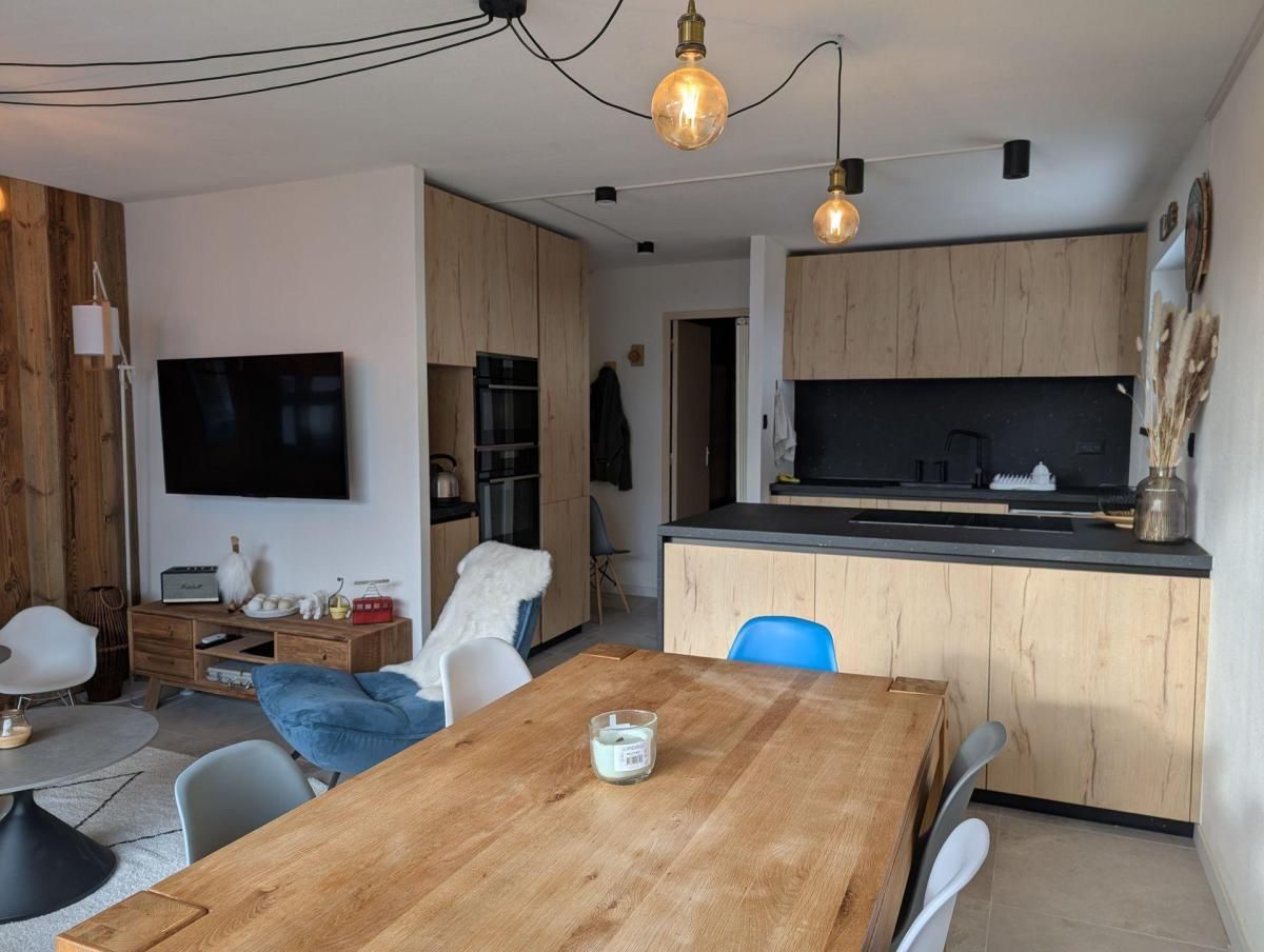 Una cocina moderna con armarios de madera, encimera negra y horno empotrado.
