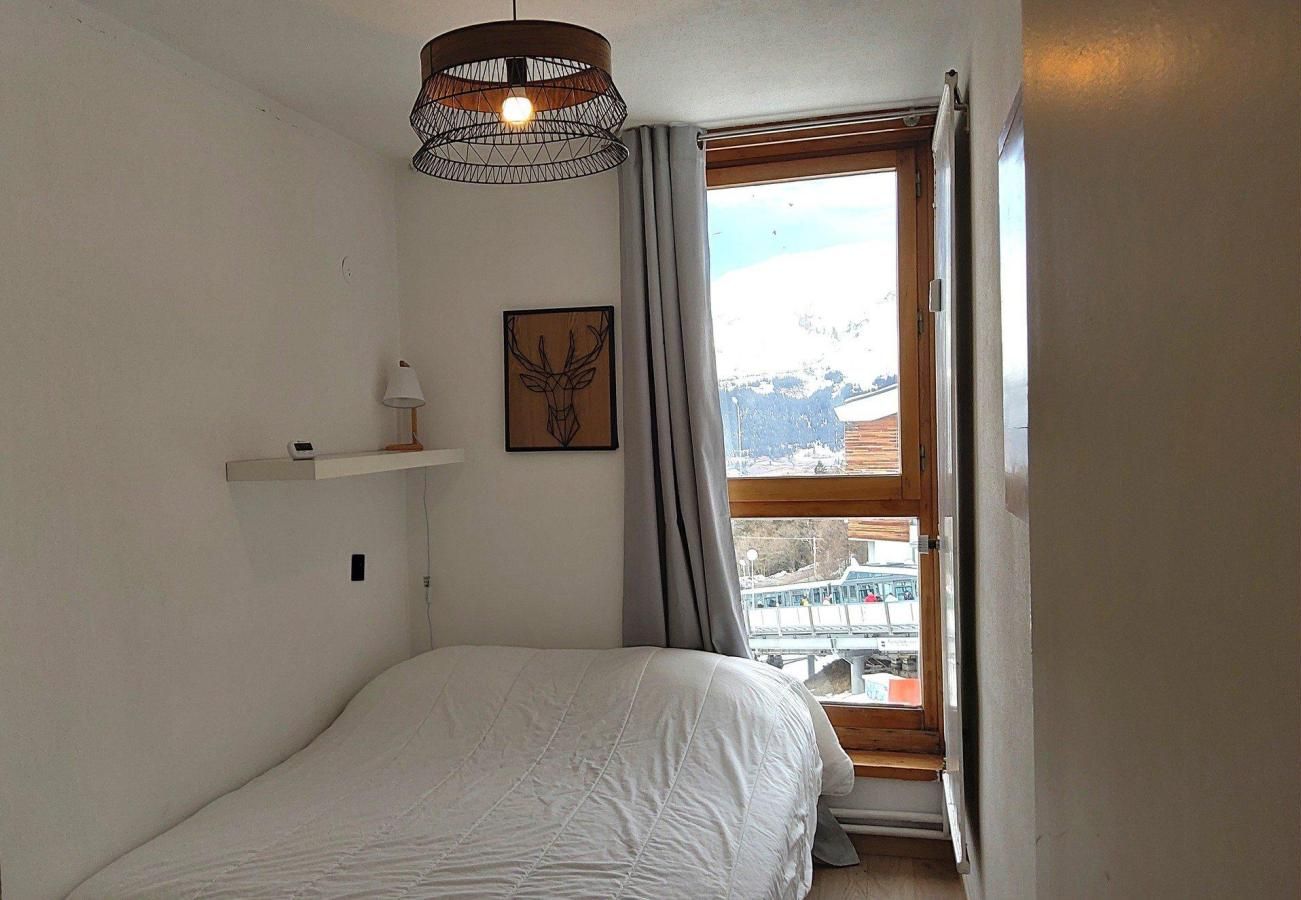 A bedroom with a bed, a wall-mounted shelf, a picture, and a window with a view of a snowy landscape.