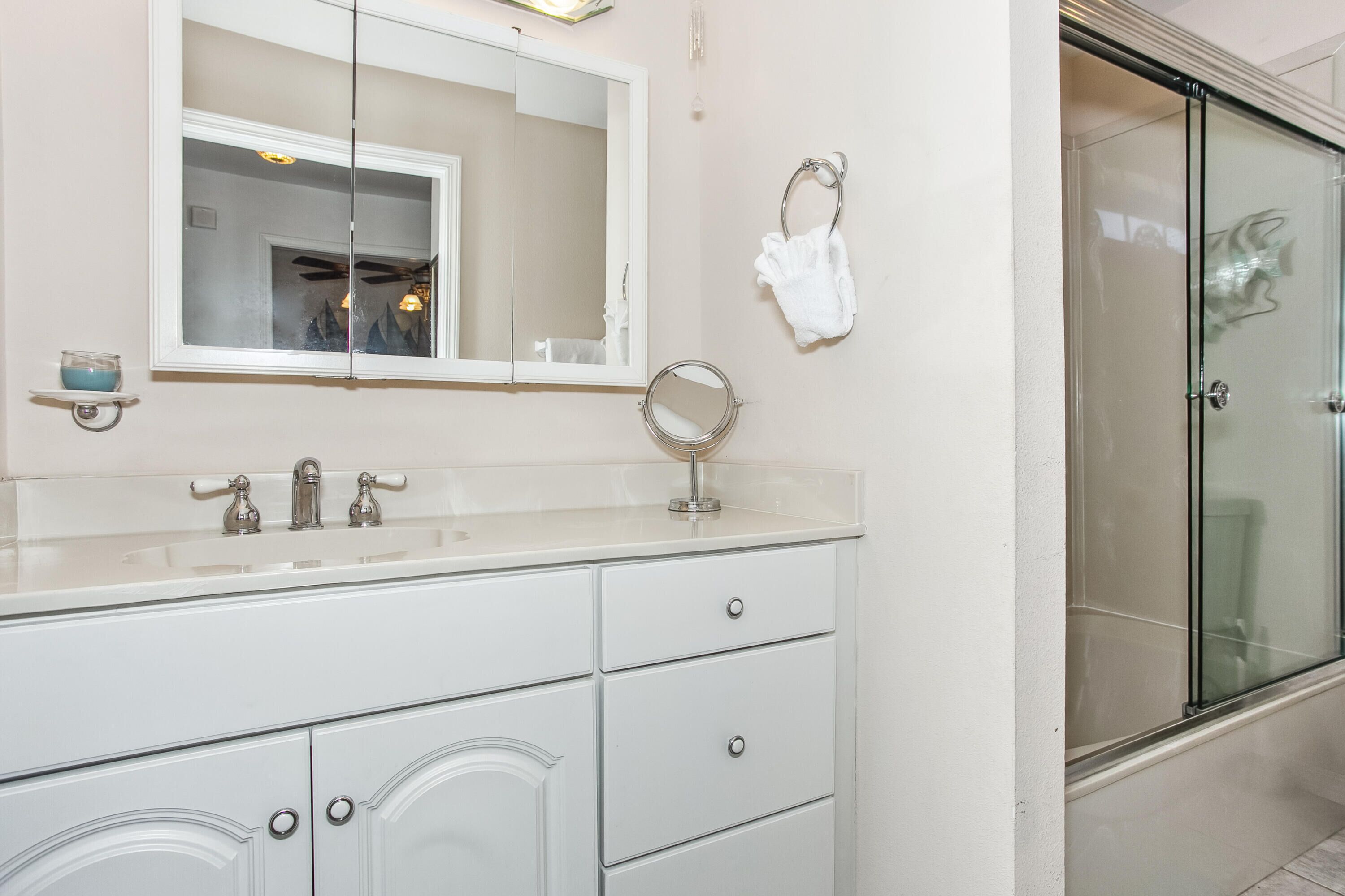 A bathroom with a white vanity, a mirror, a glass shower enclosure, and a towel rack.