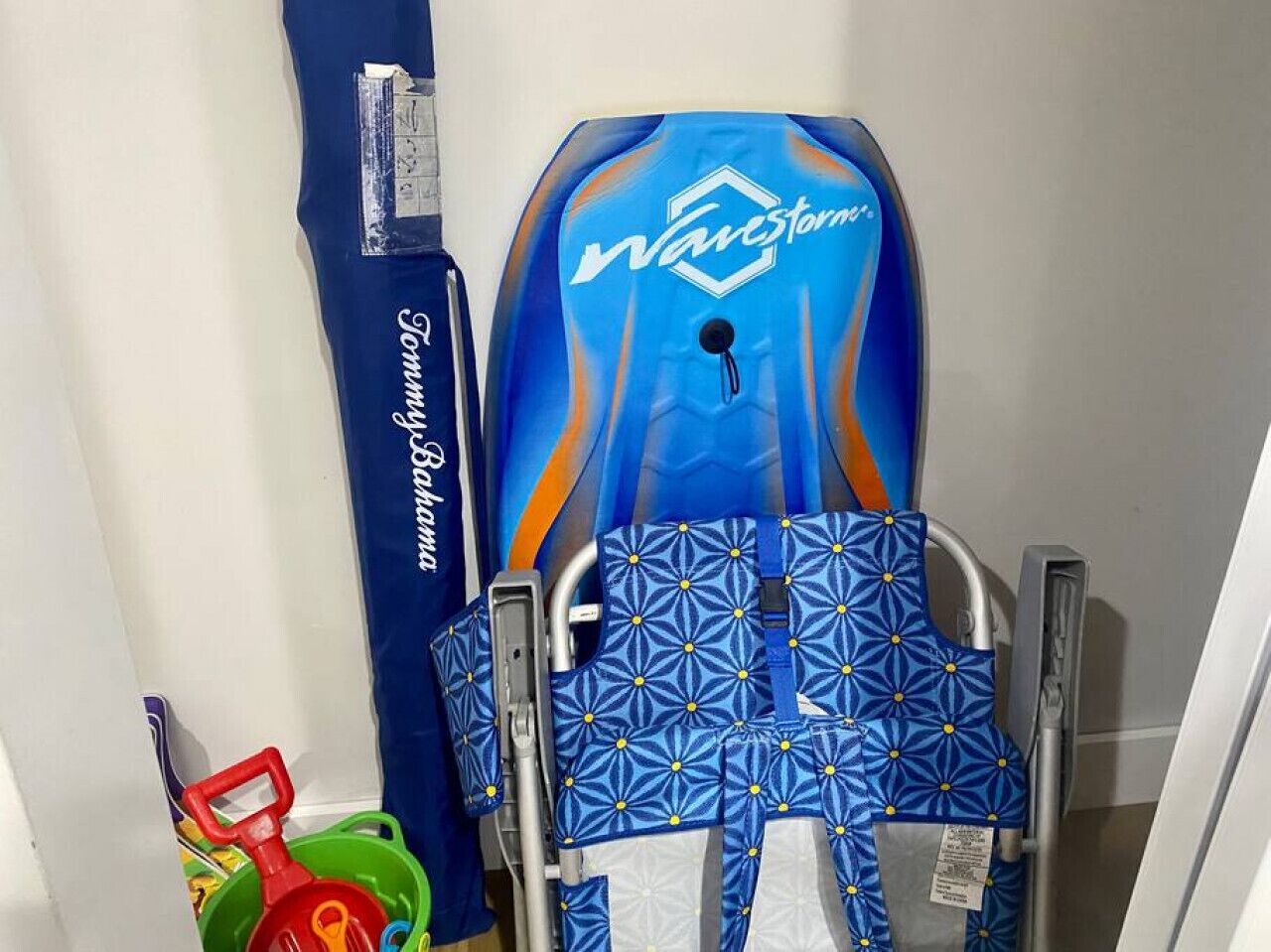 A wheelchair with a blue and orange design, a blue towel, and a red and green toy.