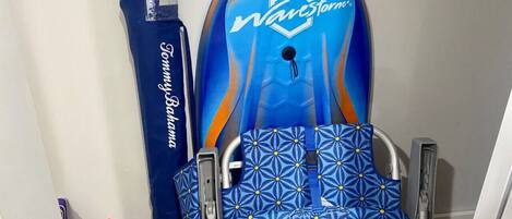 A wheelchair with a blue and orange design, a blue towel, and a red and green toy.