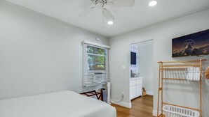 A bedroom with a bed, a ceiling fan, a window with blinds, a wooden drying rack, and a wall-mounted TV. - Steps To Beach, Main St, Pac City | BBQ | Firepit (Huntington Beach)