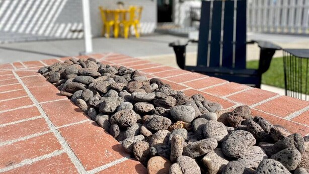 Een terras van bakstenen met een rij lavastenen.
