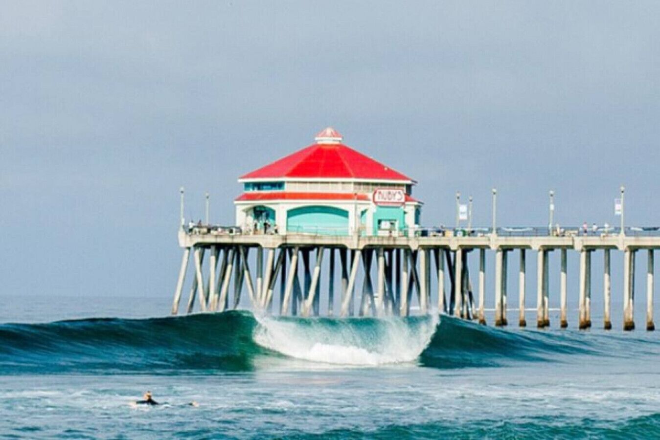 A pier with a red-roofed structure, likely a lookout or small building, extending into the ocean.