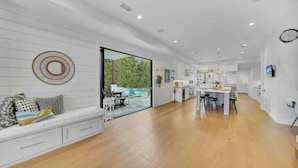 A spacious kitchen with a dining area, a large window, and a seating area with a sofa and cushions. - Rooftop Ocean Views / 2min Walk To Beach / Private Pool (Huntington Beach)