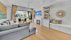 A modern living room with a grey sofa, a fireplace, and a view of the outdoors. - Rooftop Ocean Views / 2min Walk To Beach / Private Pool (Huntington Beach)