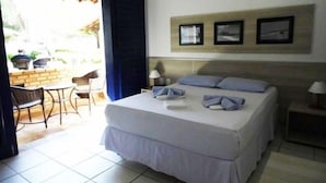 A neatly made bed with pillows and a folded towel, a small bedside table with a lamp, and a wall with three framed pictures. - Hotel Praia do Futuro (Fortaleza)