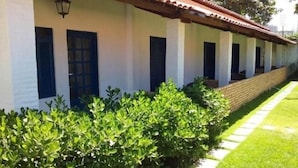 A row of white buildings with dark blue doors and windows, a brick wall, and a well-maintained hedge. - Hotel Praia do Futuro (Fortaleza)