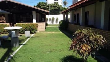 Un patio con césped cuidado, una mesa y sillas, y una planta en maceta.