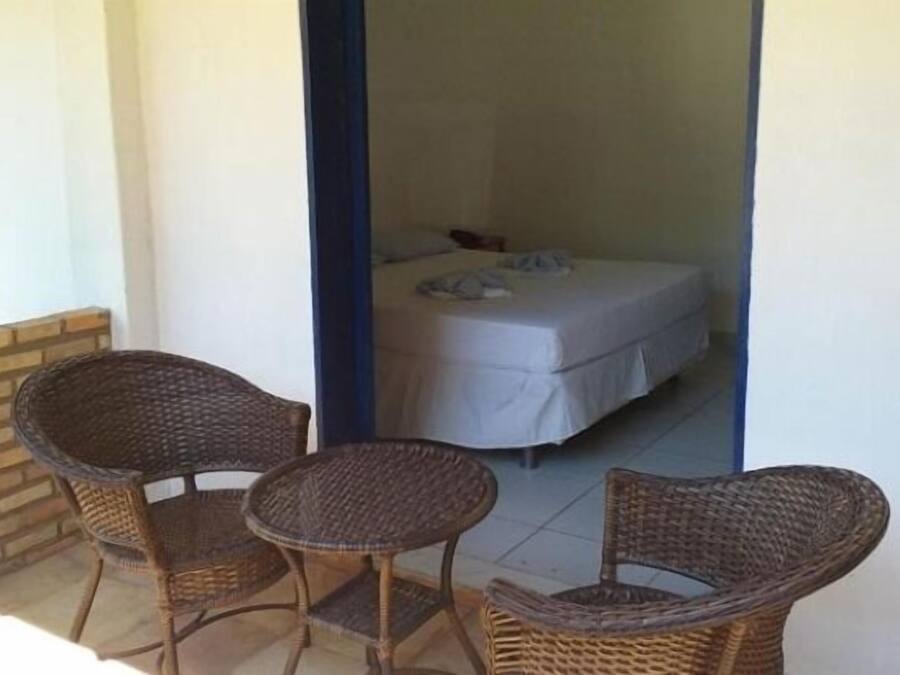 Una habitación pequeña con una cama, una mesa y dos sillas de mimbre.