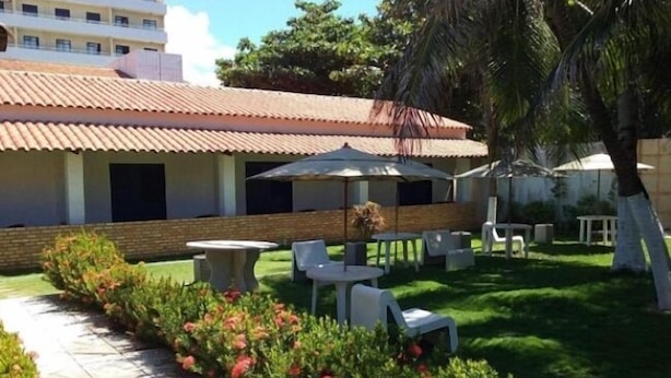 A courtyard with outdoor seating, a covered area, and a building with a tiled roof. - Hotel Praia do Futuro (Fortaleza)