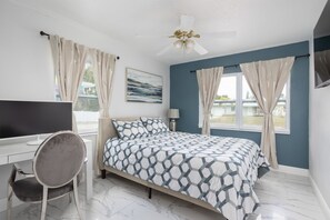 A bedroom with a bed, a desk, a chair, a ceiling fan, and a window with curtains. - Beautiful Vacation Home in Melbourne (Melbourne)