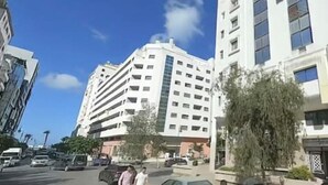 A multi-story building with a flat facade, several windows, and a visible storefront with signage.