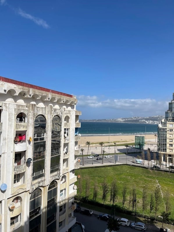 A multi-story building with balconies overlooking a beach and ocean.