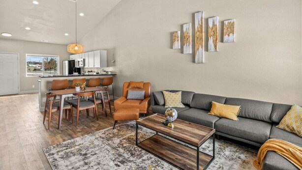 Una sala de estar moderna con un sofá gris, una mesa de centro de madera y un comedor con mesa y sillas.