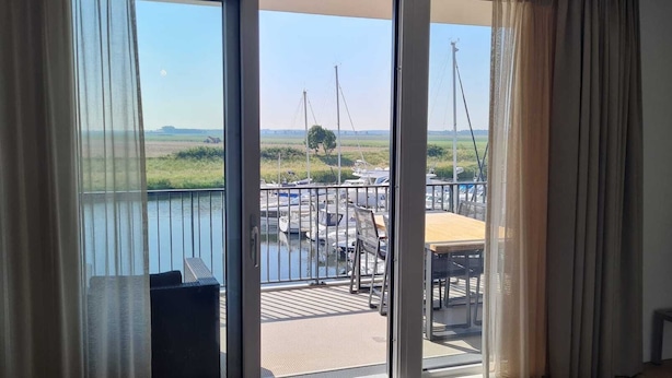 Een balkon met uitzicht op een jachthaven, een tafel en stoelen.