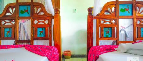 A room with two wooden beds, each with a framed picture of a peacock.