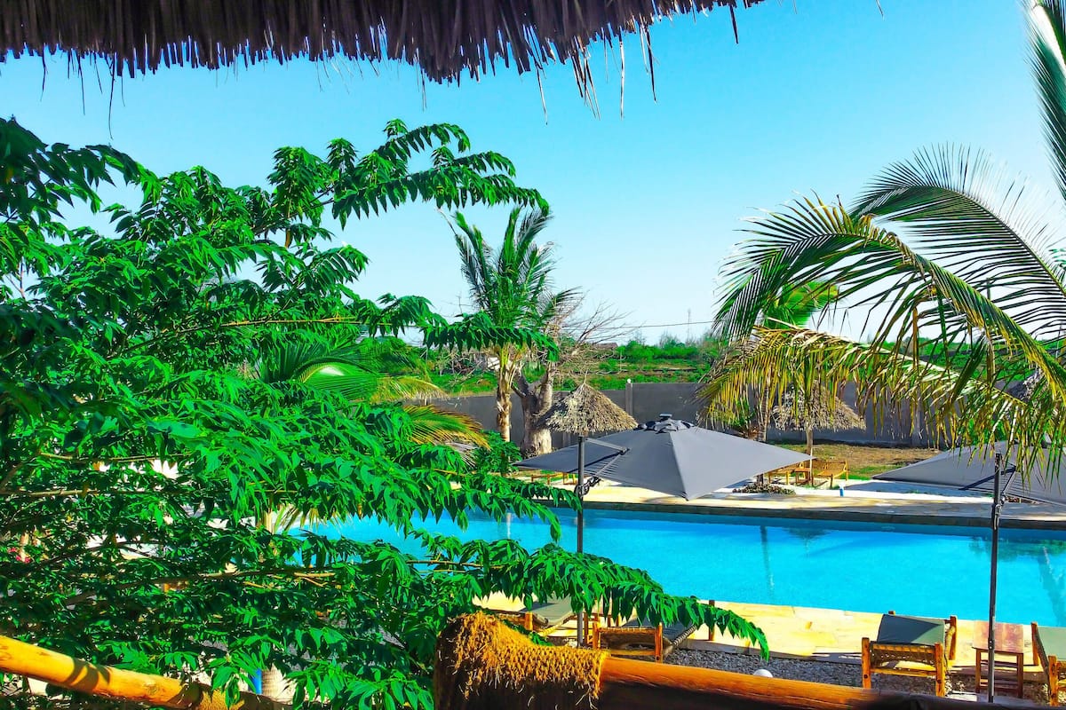 A pool area with lounge chairs and a thatched-roof structure.