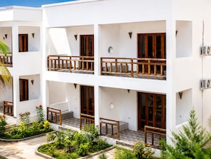 Un immeuble à plusieurs étages doté de balcons, d’un espace jardin et de climatiseurs.