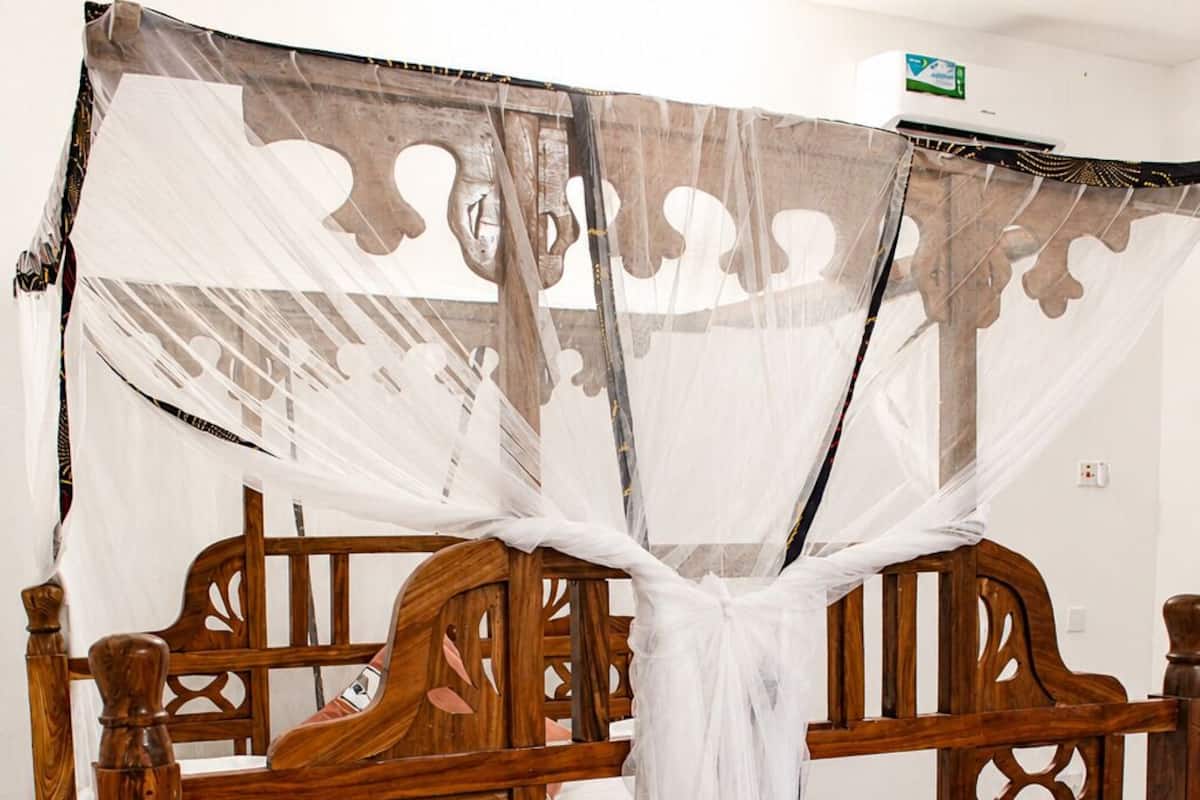 A wooden bed with a canopy, a bedside table, and a patterned floor.