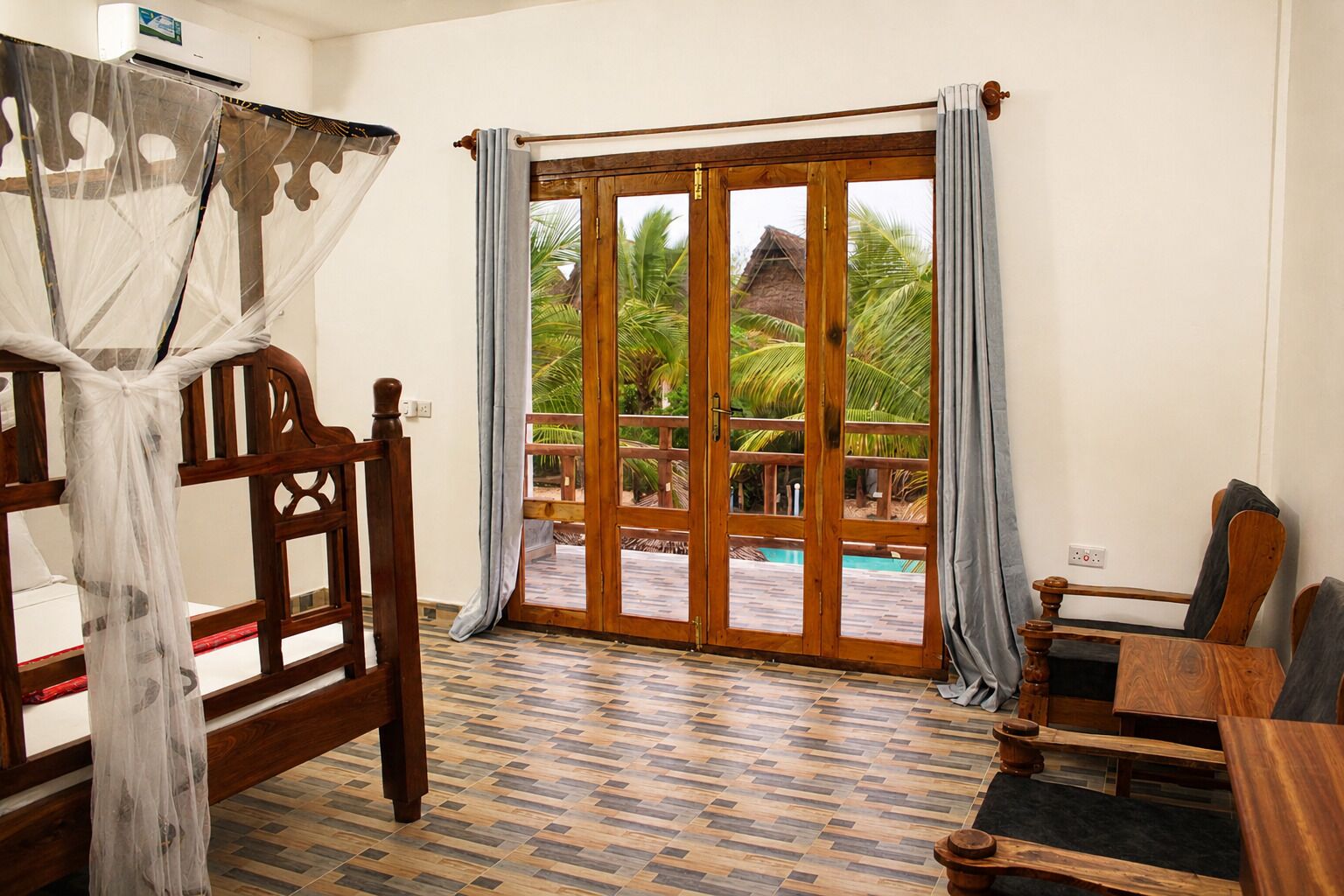 Ein Zimmer mit Bett, Tisch und Blick auf Pool und Palmen.