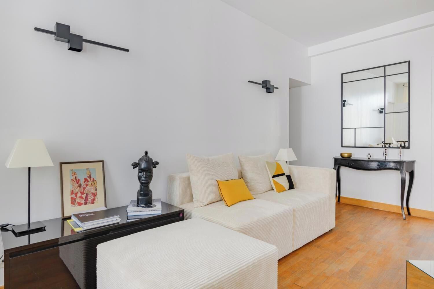 A modern living room with a sofa, a coffee table, a side table, a lamp, a framed picture, and a sculpture.
