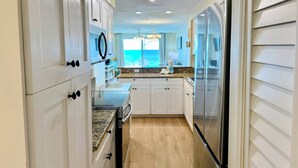 A modern kitchen with white cabinets, granite countertops, and stainless steel appliances. - Palms 204 Beachfront Condo with Free Beach Service! (Fort Walton Beach)