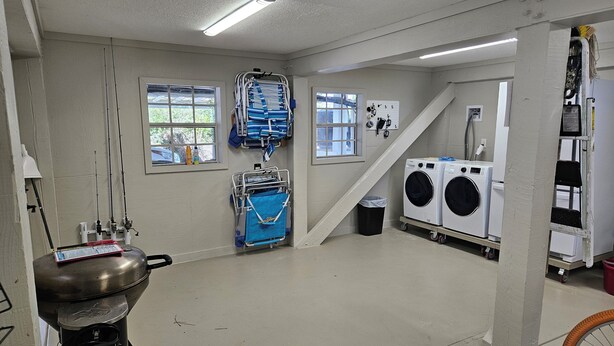 A laundry room with a washing machine, dryer, and ironing station. - Bayfront with Gulf and Pool Access (Port Saint Joe)