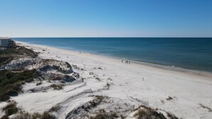 A beach with a sandy shore, a few people walking, and a building in the background. - Bayfront with Gulf and Pool Access (Port Saint Joe)